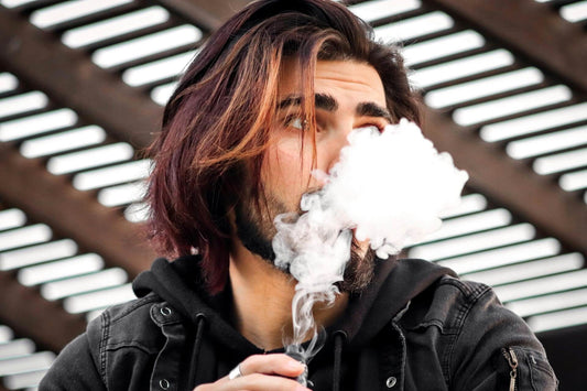 close up image of a man with long hair vaping nicotine free e liquids